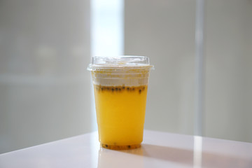 Plastic glass of iced passion fruit tea with layer of cream cheese foam on blurred background and copy space, Traditional Taiwanese and Chinese Beverage.