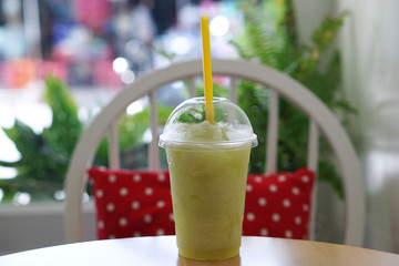 A plastic glass of lemon mint frappe on wooden table and blurred background, Refreshing summer drink.