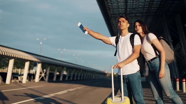Happy couple in love catching a taxi standing with luggage near the airport, traveling. The concept of rest, vacations, advertising taxi service