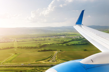 Aircraft landing on the runway, view of wing and green field