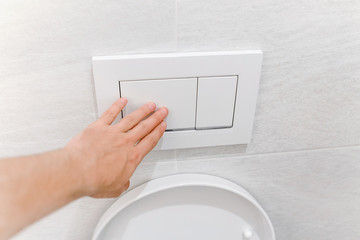 Hand pressing toilet flush button