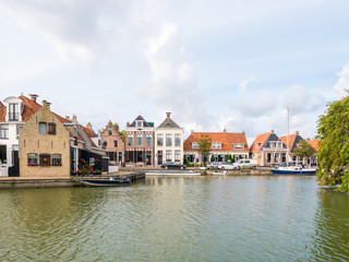 Fototapeta na wymiar Harbour with boats and quayside with houses in old town of Makkum, Friesland, Netherlands