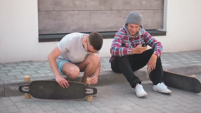 Hipster skateboarders sitting on the street with skateboards, street skateboarding lifestyle concept