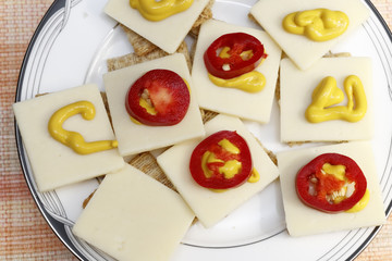 Red Jalapenos, Cheddar Cheese, Mustard on Crackers. Snack of crackers with red jalapenos, cheese and mustard. Appetizer of cheese mustard pepper slices.
