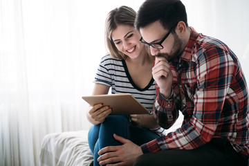 Fototapeta premium Young happy couple using tablet in bedroom