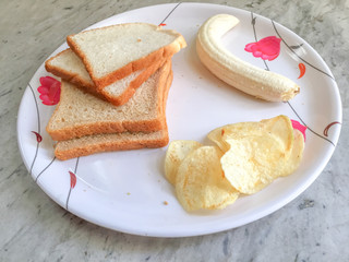 Breakfast consisting of bread, banana and chips