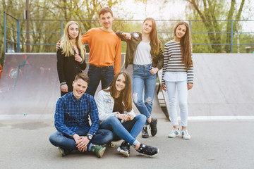 Summer holidays and teenage concept - group of smiling teenagers with skateboard hanging out outside.