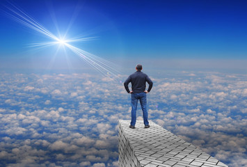 Man stands over the clouds and looks at a distant bright star above the horizon