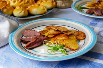Fried potatoes, goose breast and green onions