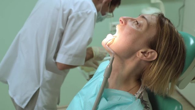 Dentist treats a tooth of beautiful female patient in dental clinic