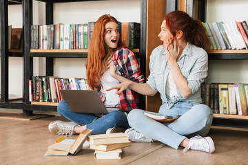 Two surprised teenage girls sitting on a floor