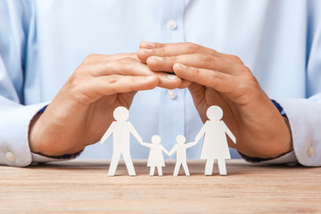 Medical or travel insurance. Man covers the family with his hands from his father, mother, son and...