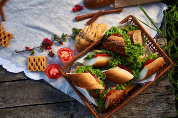 Picnic basket full with sandwiches, baguette and croissant on a homespun tablecloth, flat lay, selective focus