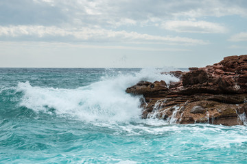The waves breaking on a stony beach, forming a big spray