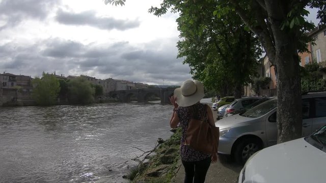 Young woman with a hat strolling along the river Aude in the French town of Limoux, Languedoc in the south of France