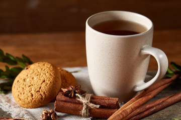 Traditional Christmas tea concept with a cup of hot tea, cookies and decorations on a wooden table, selective focus