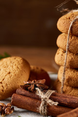 Christmas composition with pile of cookies, cinnamon and dried oranges on light wooden background, close-up.