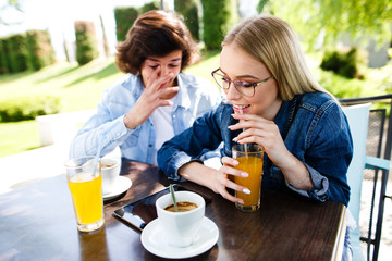 Young romantic couple spending time together - sitting in cafe's garden, drinking juice and having fun