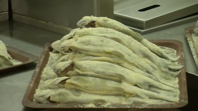 Fish fried in a frying pan until golden brown,Pieces of fresh fish are fried in a frying pan in flour and they are turned with a fork.Chef is cooking fish.Preparing of fish for frying.
