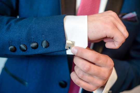 A man in a blue suit, button cufflinks