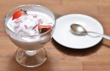 Melted vanilla ice cream with strawberry slices, mixed in a glass bowl.