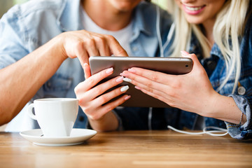 Young Charming Couple Using Tablet While Sitting Together And Drinking Coffee