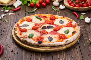 rustic italian pizza Margarita with mozzarella, cherry tomatoes and basil leaves on wooden background