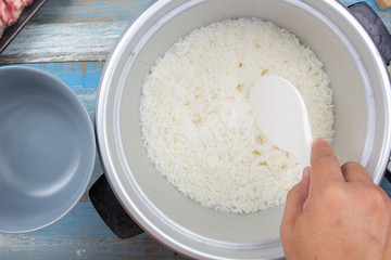 Cooked rice on plastic ladle in electric rice cooker