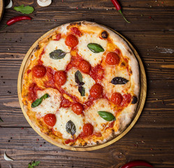 rustic italian pizza Margarita with mozzarella, cherry tomatoes and basil leaves on wooden...