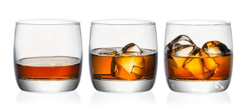 Whiskey in three glasses with ice on a white background