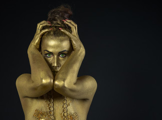 woman fully dressed in gold  on black background