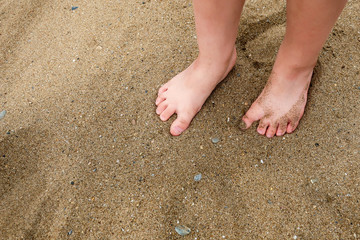 A little girl's / child's feet in the sand on a beach. Blank empty copy space for text.