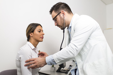 Male doctor examines a female patient with stethoscope