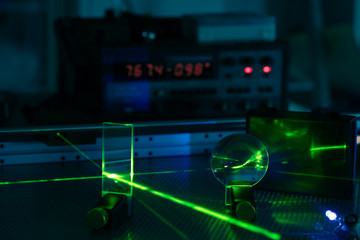 Green laser on optical table in a quantum optics lab.