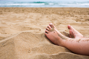 Child feet in the sand on a beach. Concept for traveling with children / family vacation and holiday.