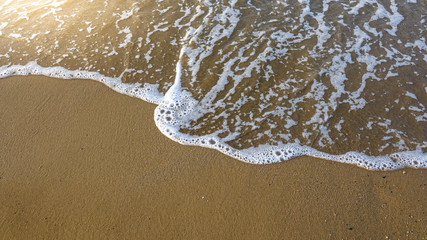Soft beautiful ocean wave on sandy beach in the sunset. Crete, Greece.