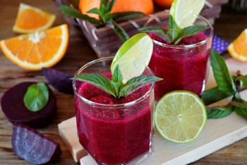 Smoothie with beet and orange in a glass decorated with mint and a slice of lime