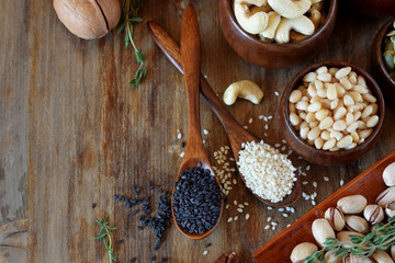 Different nuts and seeds in wooden spoons and bowls on a table