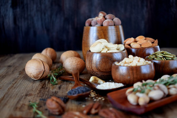 Different nuts and seeds in wooden spoons and bowls on a table