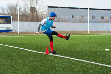 Boy kicking soccer ball on sports field