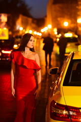 Night city with princess in celebrity style. night city with woman in red dress wait for taxi.