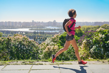 Woman runner run commutes to work with backpack, city morning run commuting and fitness concept,...