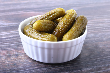 Bowl with pickled gherkins, cucumbers on wooden background close up. Pickles.