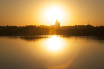 Beautiful sunset on a lake with church dome on a sunset background