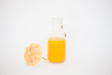 Orange juice in the original glass bottle and paper umbrellas on a white background