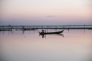 un p&ecirc;cheur sur une petite barque sur un lac 