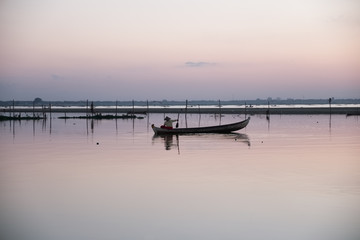un pêcheur sur une petite barque sur un lac 