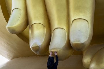 une dame qui m&eacute;dite devant la main g&eacute;ante d&rsquo;un bouddha
