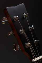 Six-stringed acoustic guitar head with tuning pegs