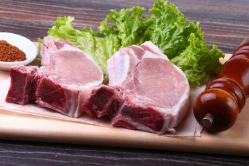 Raw pork steak with spices Leaves lettuce on wooden cutting board. Ready for cooking.